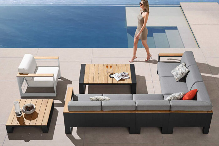 Composition salon d'angle extérieur haut de gamme avec table basse et fauteuil de jardin, présentés sur une terrasse au bord d'une piscine (Visconti).
