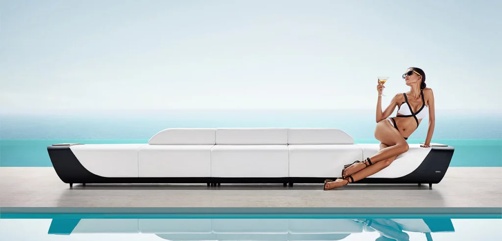 Mobilier de jardin haut de gamme Onda chez Maison BELLOEIL : un grand canapé blanc au bord d'une piscine.